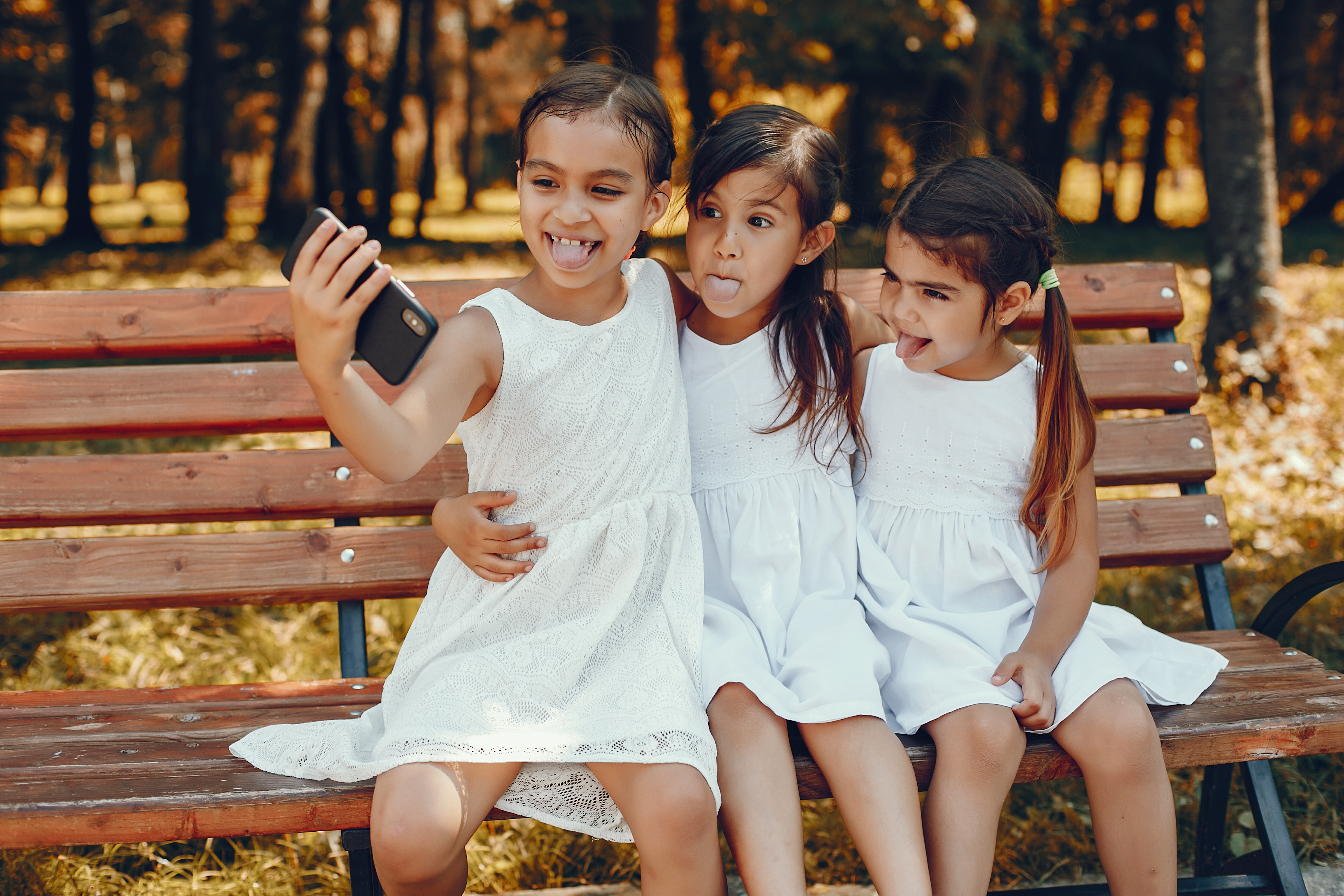 Three little sisters sitting in a summer park